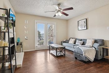 A living room with a grey couch and a ceiling fan